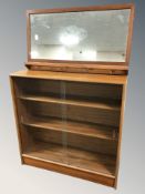 A 20th century teak sliding glass door bookcase, width 91 cm, and a mirrored coat rack.
