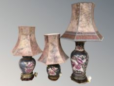 Three graduated decorative ceramic table lamps with shades, tallest 93 cm.