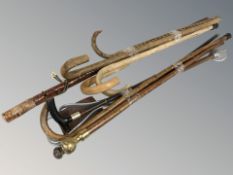 A bundle of walking sticks, shooting stick, cane with compass inset pommel, etc.