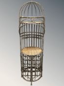 A wrought metal and wicker stand incorporating a bottle rack beneath, height 169 cm.