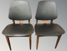 A pair of 20th century teak and black vinyl dining chairs.