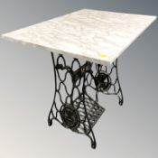 A cast iron Singer treadle sewing machine base with modern faux marble top, 85 cm x 59 cm x 74 cm.