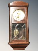 An early 20th century wall clock with silvered dial, with pendulum and key, length 80 cm.