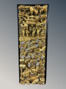 A Chinese heavily carved lacquered and gilt relief wall panel depicting figures in traditional