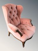 A pair of wingback armchairs in salmon dralon fabric.