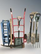 A sack barrow, a group of shovels, spades and a pair of car ramps.