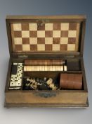 An Edwardian mahogany games box containing chess pieces, draughts pieces, chess.