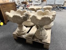 A pair of scalloped edged concrete urns on stands.