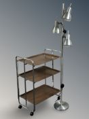 A stainless steel three tier trolley, together with an adjustable floor lamp.