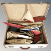 A suitcase containing plastic and wooden vintage model sailing boats, etc.
