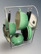 A metal pan stand containing Le Creuset green enamel pans.