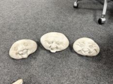 Three concrete face ornaments.