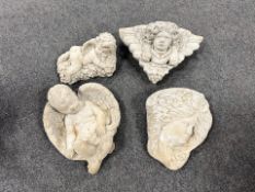 Four concrete cherub and face ornaments.