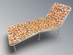 A 1970's metal garden lounger with floral cushion,