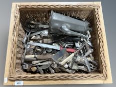 A wicker crate of pewter coffee pot and a large quantity of flat wares