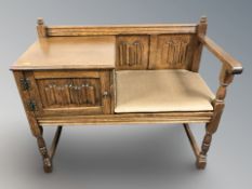 An oak linen fold telephone seat, 94 cm x 46 cm x 78 cm.