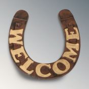 A cast iron horseshoe welcome sign, width 27 cm.