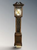 A reproduction carved oak longcase clock with pendulum and weights,