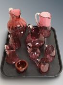 A group of cranberry glass jugs, tallest 19 cm.
