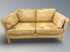 A late 20th century Danish faded tan leather two seater settee,