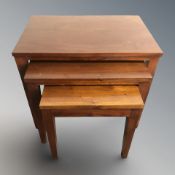 A reproduction hard wood nest of three tables,
