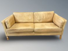 A late 20th century Danish faded tan leather three seater settee,