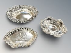 A pierced silver oval dish, width 12 cm, plus two further dishes.