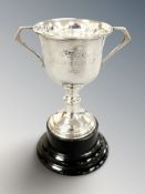 A silver twin-handled trophy cup, engraved 'Wellwishes Cup 1955', on ebonised plinth, height 15.