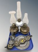 Three oil lamps, a pair of hammered pewter candlesticks, pewter dish, horse brasses.