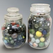 Two glass jars containing assorted marbles.