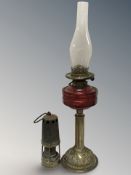 A brass oil lamp with cranberry glass reservoir, height 65 cm,