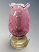 A brass and cranberry glass oil lamp, height 50 cm.