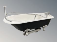 An enamelled metal roll top bath with chrome tap fixtures raised on silvered metal claw and ball