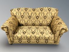 A two seater Edwardian settee upholstered in Arts and Crafts style floral upholstery,