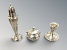A loaded silver sifter, a similar candlestick and a twin-handled vessel with lid.