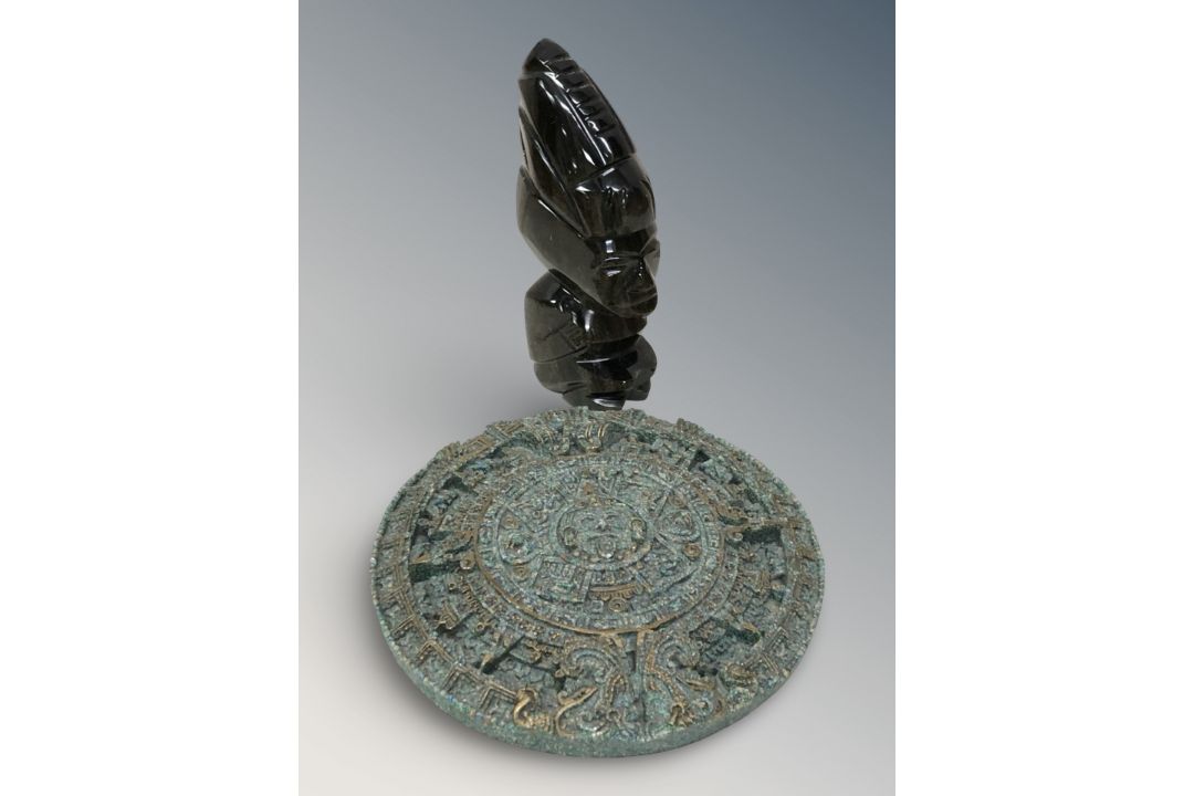 A carved golden obsidian Aztec style figurine and a reproduction Aztec calendar plaque,