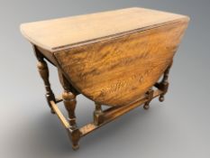 A reproduction oak gateleg drop leaf table, 150 cm L x 107 cm W x 75 cm H.