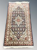 An Iranian woolen rug, signed to one end, 156 cm x 74 cm.