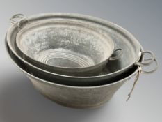 Three galvanised wash tubs, largest 90 cm wide.