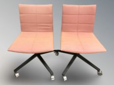 A pair of swivel desk chairs.