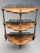 A Victorian figured walnut carved fret work three tier what-not,