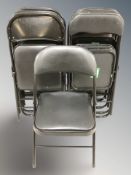 Eleven folding metal and black vinyl chairs