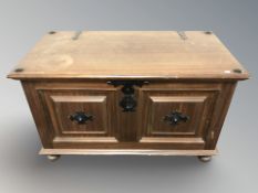 A reproduction hardwood blanket chest with metal mounts,