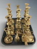 Five pairs of brass candlesticks, fire poker, pair of tongs, figural bell and an ashtray.