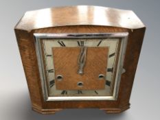 An Art Deco oak mantel clock with silvered dial, with pendulum and key, height 22 cm.