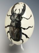 An ostrich egg painted with a beetle, signed Kate Arnold, 2016, height 16 cm.