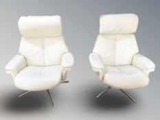 A pair of Scandinavian cream leather swivel armchairs.