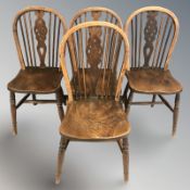A set of four elm wheel back dining chairs.