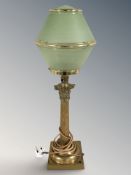A brass Corinthian column table lamp with green and gilt glass shade, height 62 cm.