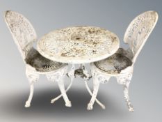 A painted cast metal circular garden patio table, diameter 68 cm, and a pair of chairs.
